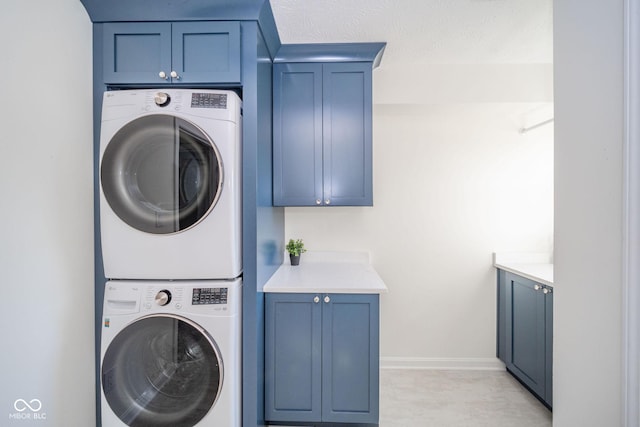 washroom with stacked washer and dryer, baseboards, and cabinet space