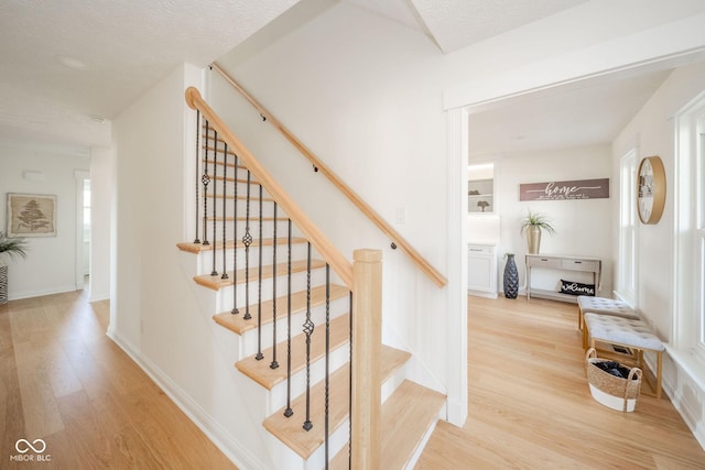 staircase featuring baseboards and wood finished floors