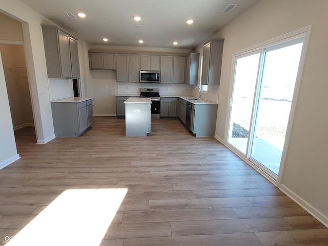 kitchen with a sink, visible vents, appliances with stainless steel finishes, gray cabinets, and plenty of natural light