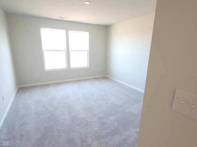 carpeted spare room with visible vents and baseboards