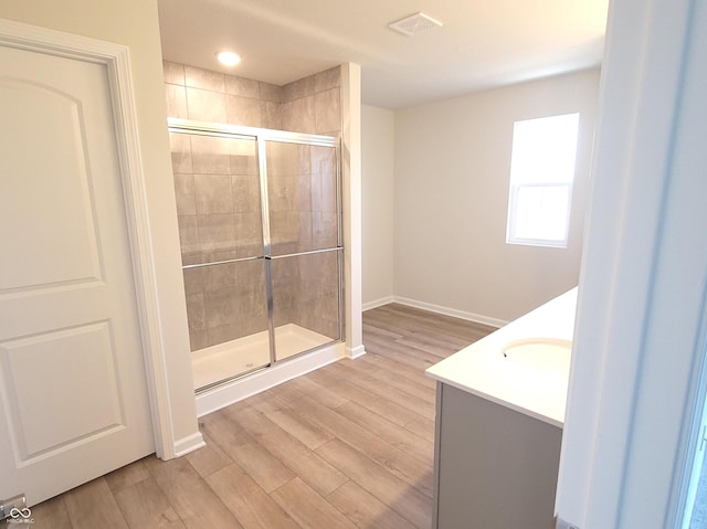 full bathroom featuring a stall shower, baseboards, visible vents, wood finished floors, and vanity