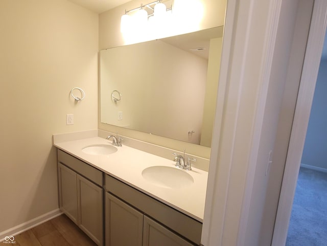 bathroom featuring wood finished floors, a sink, baseboards, and double vanity