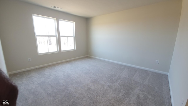 carpeted empty room featuring baseboards and visible vents