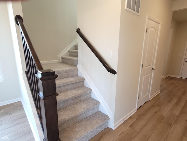 stairs with visible vents, baseboards, and wood finished floors