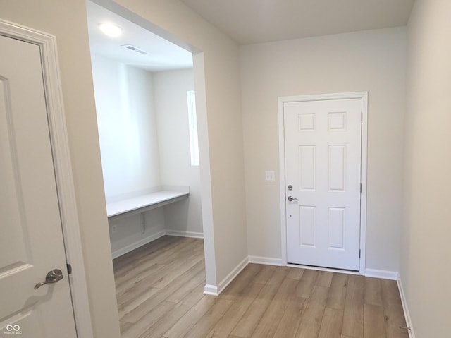 foyer with light wood-style floors, baseboards, and visible vents