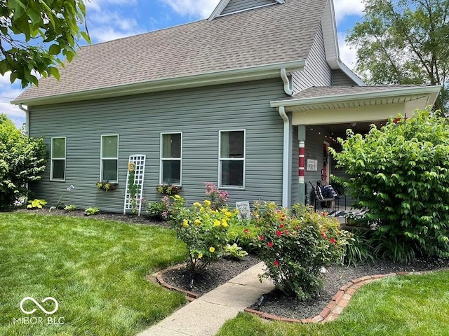 rear view of property featuring a shingled roof and a lawn