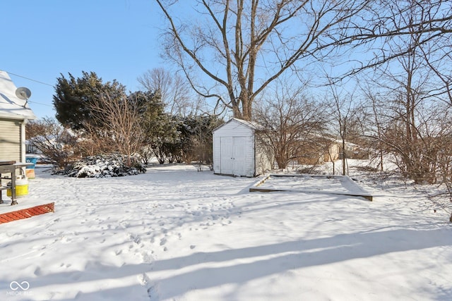 yard layered in snow with a storage unit and an outdoor structure