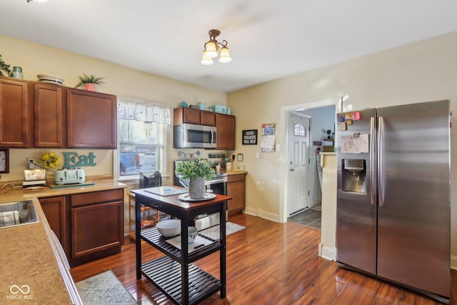 kitchen featuring baseboards, dark wood-style floors, appliances with stainless steel finishes, light countertops, and a sink