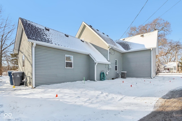 snow covered back of property featuring central AC unit