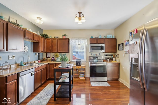 kitchen featuring brown cabinets, dark wood finished floors, stainless steel appliances, light countertops, and a sink