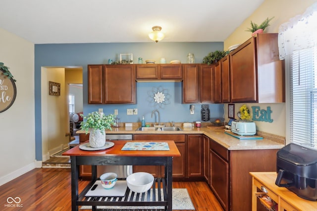 kitchen with dark wood-type flooring, baseboards, light countertops, and a sink