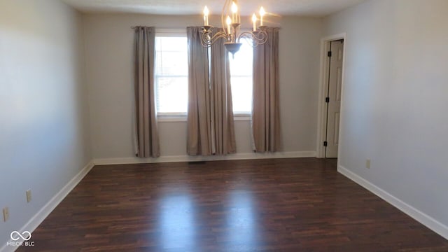 unfurnished room featuring baseboards, wood finished floors, and a notable chandelier