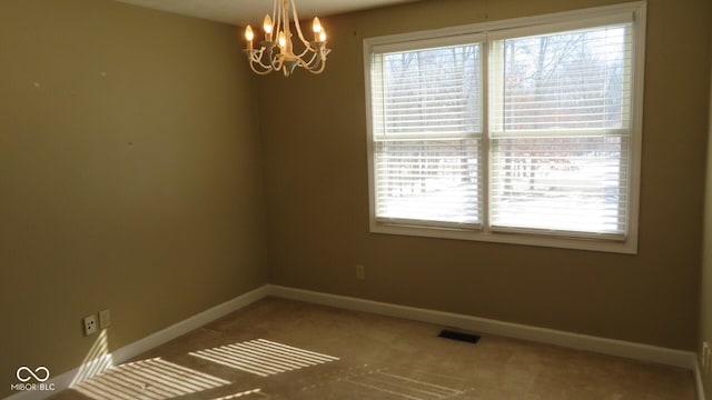 unfurnished room featuring a chandelier, a wealth of natural light, visible vents, and baseboards