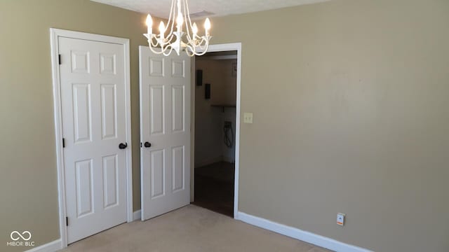 interior space with baseboards, a chandelier, and light colored carpet