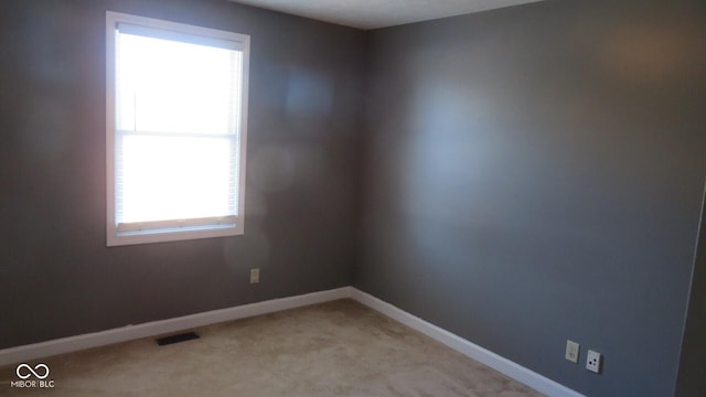 unfurnished room with light carpet, visible vents, and baseboards