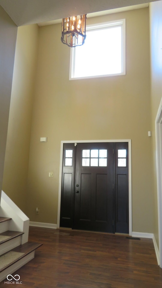 entrance foyer with a towering ceiling, baseboards, stairs, dark wood-style floors, and an inviting chandelier