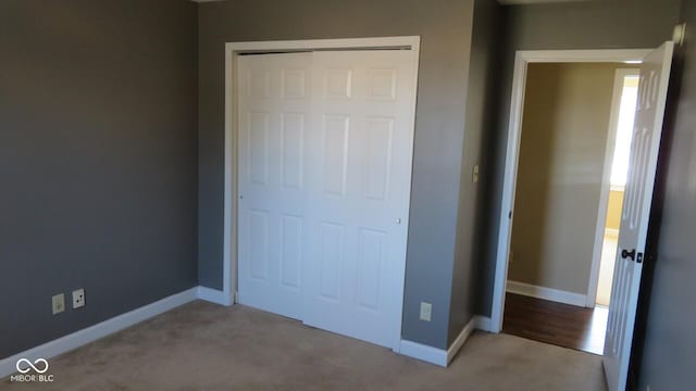 unfurnished bedroom with carpet floors, a closet, and baseboards