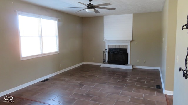 unfurnished living room with visible vents, a fireplace, baseboards, and a ceiling fan