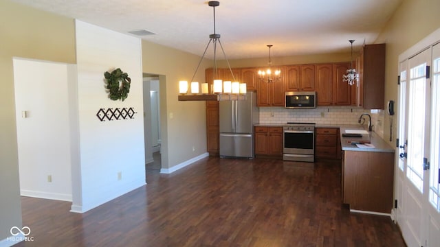 kitchen featuring dark wood-style floors, tasteful backsplash, appliances with stainless steel finishes, brown cabinetry, and a sink