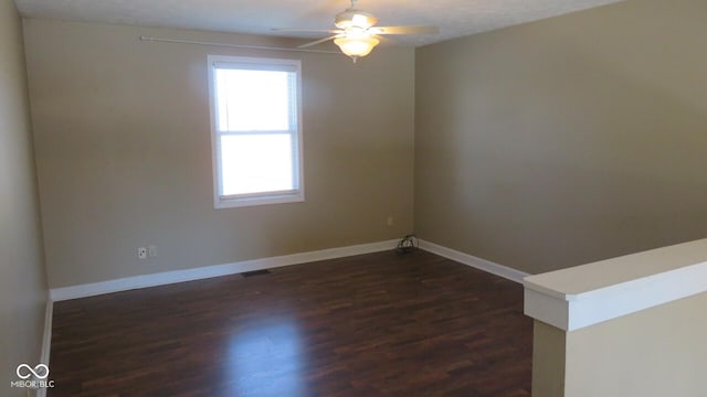 unfurnished room with ceiling fan, baseboards, and dark wood-type flooring