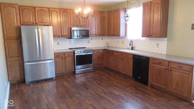 kitchen featuring stainless steel appliances, dark wood-type flooring, a sink, tasteful backsplash, and decorative light fixtures