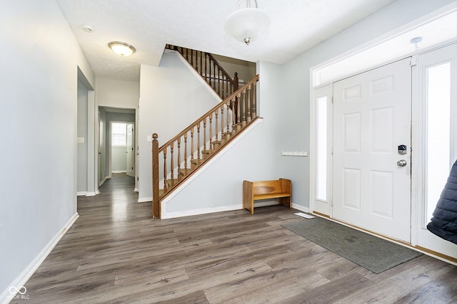 entryway with stairs, dark wood-type flooring, a textured ceiling, and baseboards