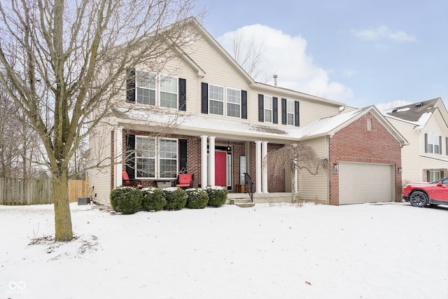 traditional-style home with covered porch, brick siding, an attached garage, and fence