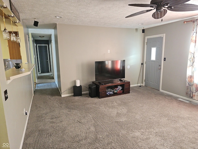 carpeted living area featuring ceiling fan, visible vents, baseboards, and a textured ceiling