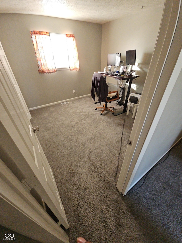 carpeted home office with a textured ceiling and baseboards