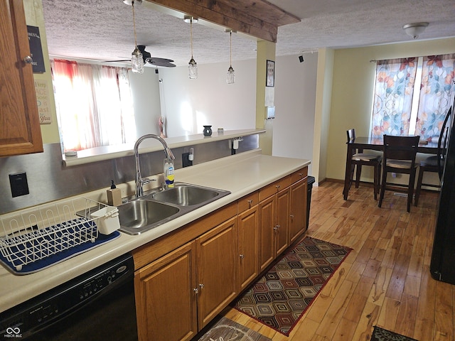 kitchen with black dishwasher, light countertops, a sink, a textured ceiling, and hardwood / wood-style flooring