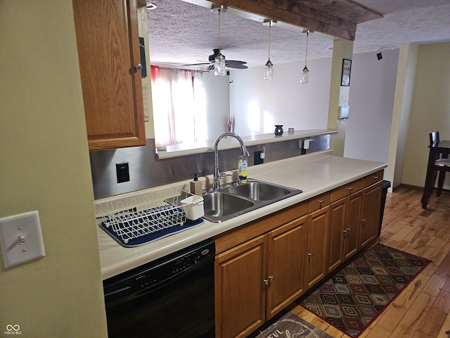 kitchen featuring a textured ceiling, hardwood / wood-style flooring, a sink, light countertops, and dishwasher