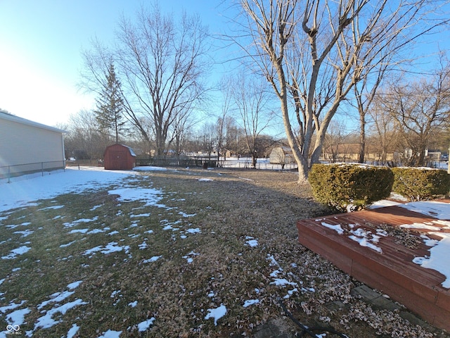 yard covered in snow with an outbuilding, fence, and a storage shed