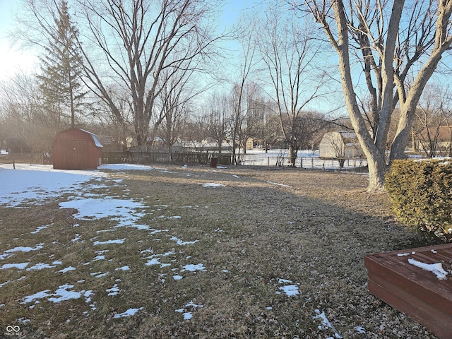 snowy yard with a shed, an outdoor structure, and fence