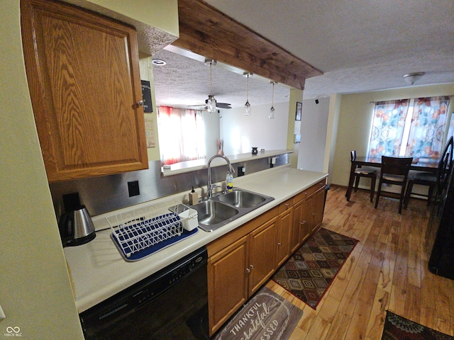 kitchen featuring brown cabinets, light countertops, a sink, a textured ceiling, and dishwasher