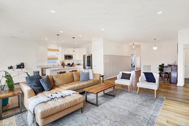 living room featuring wainscoting, recessed lighting, visible vents, and light wood-style floors