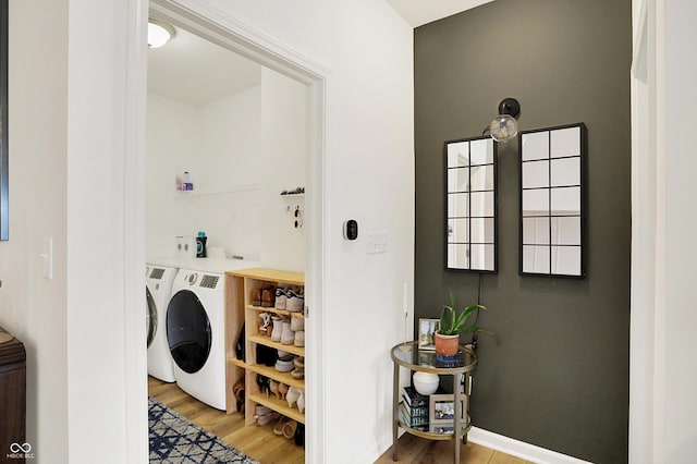 washroom featuring laundry area, separate washer and dryer, light wood-type flooring, and baseboards