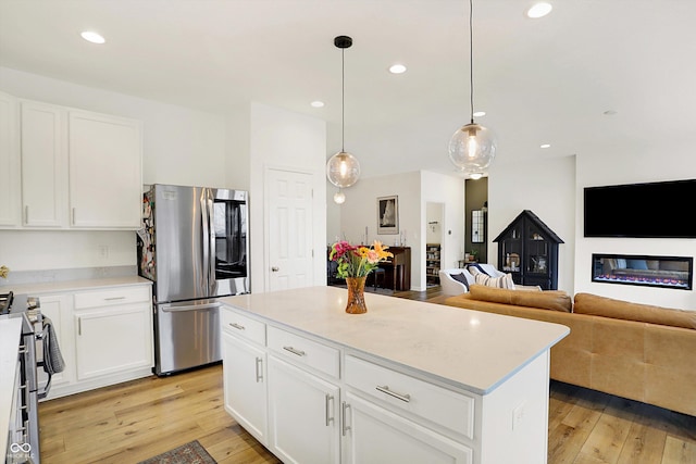 kitchen with stainless steel appliances, recessed lighting, light countertops, light wood-style floors, and a glass covered fireplace