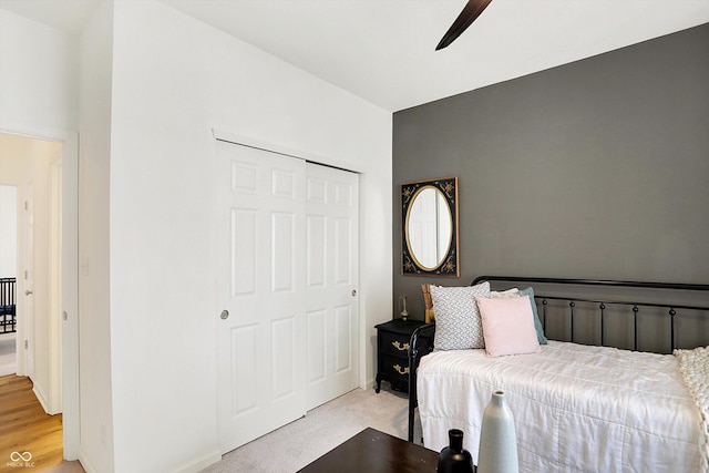 bedroom with a ceiling fan, a closet, and light carpet