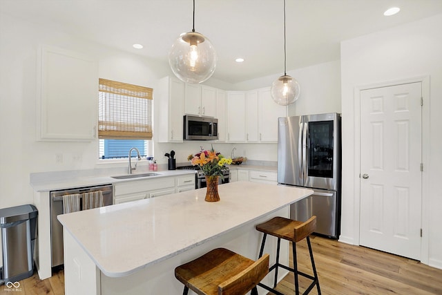 kitchen featuring a breakfast bar area, light wood-style flooring, appliances with stainless steel finishes, white cabinetry, and a sink