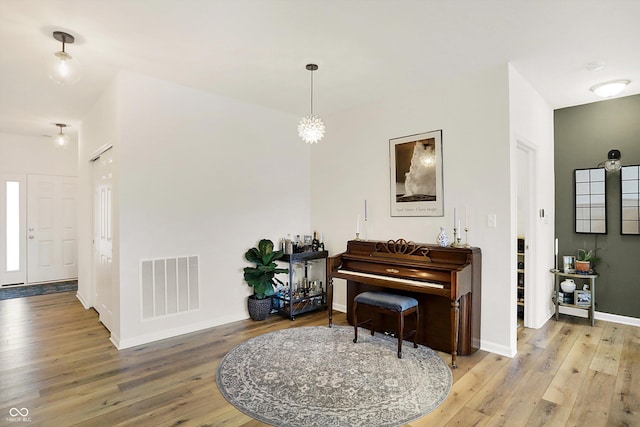 interior space featuring hardwood / wood-style flooring, baseboards, visible vents, and an inviting chandelier