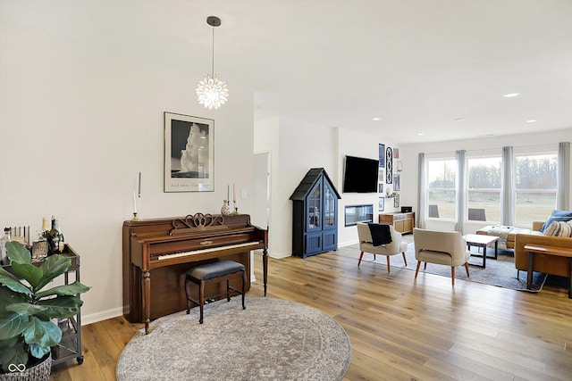 living room with recessed lighting, baseboards, light wood finished floors, and an inviting chandelier