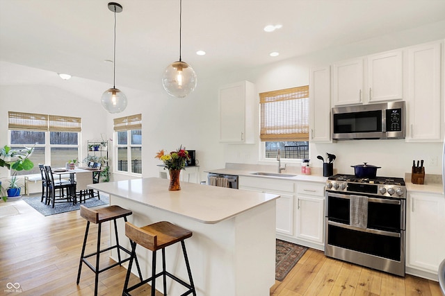 kitchen featuring light wood finished floors, a kitchen island, appliances with stainless steel finishes, and a sink