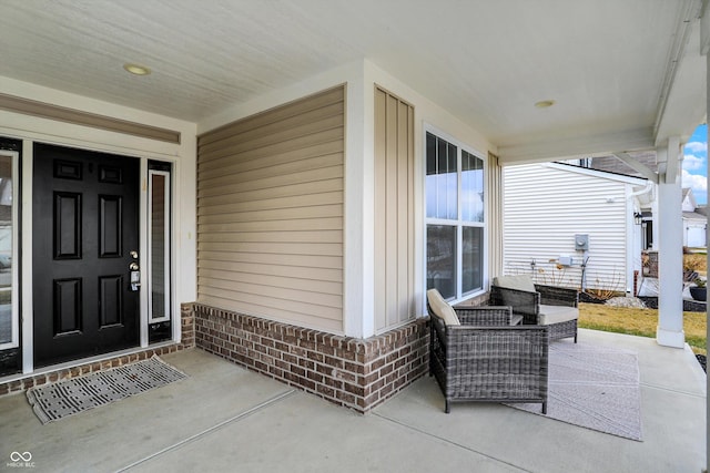 view of exterior entry featuring covered porch and brick siding