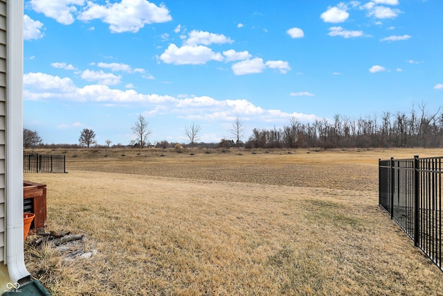 view of yard with fence and a rural view