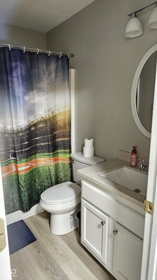 full bath featuring toilet, a textured ceiling, wood finished floors, and vanity