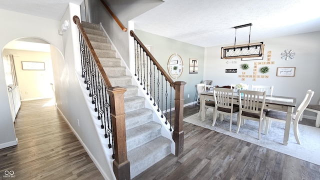 dining room featuring dark wood-style floors, arched walkways, and baseboards