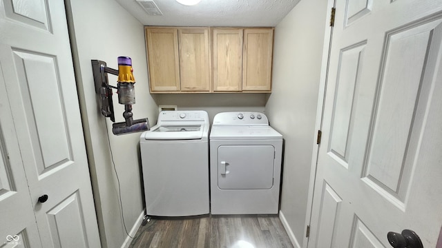 laundry room with cabinet space, visible vents, dark wood-style floors, a textured ceiling, and separate washer and dryer