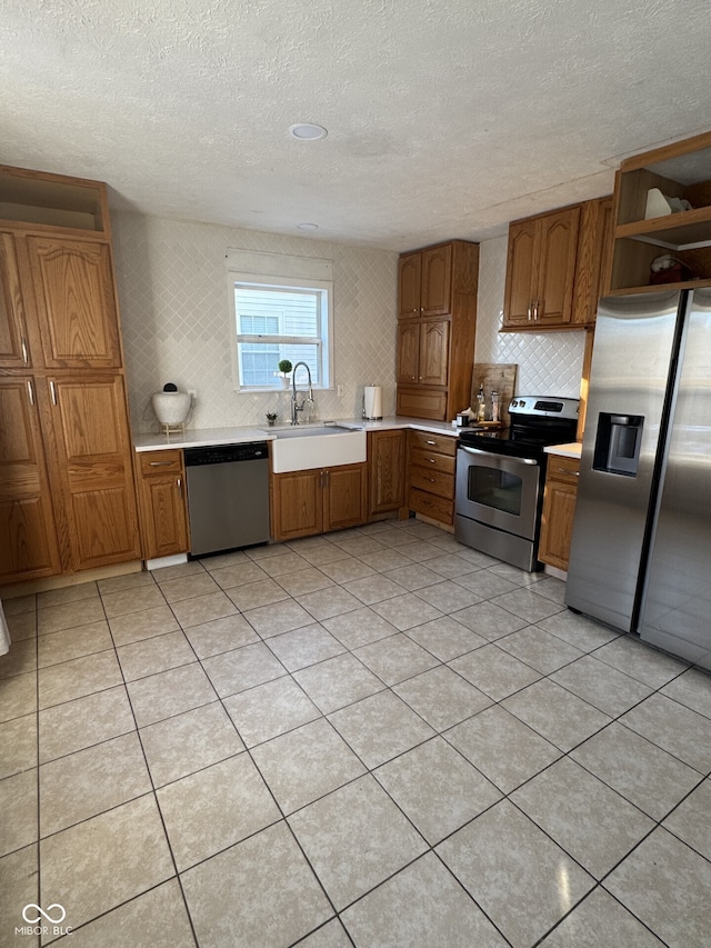 kitchen with brown cabinetry, stainless steel appliances, a sink, and light countertops