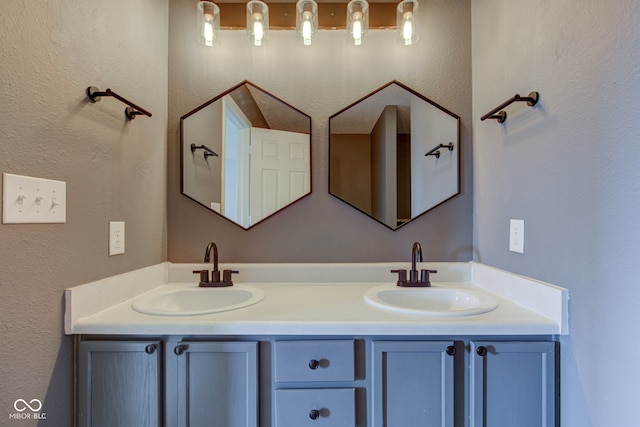 bathroom featuring a sink, double vanity, and a textured wall