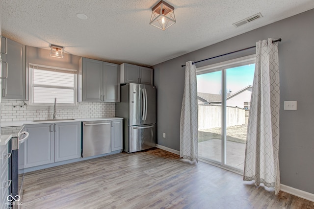 kitchen with visible vents, a sink, gray cabinetry, light countertops, and stainless steel appliances